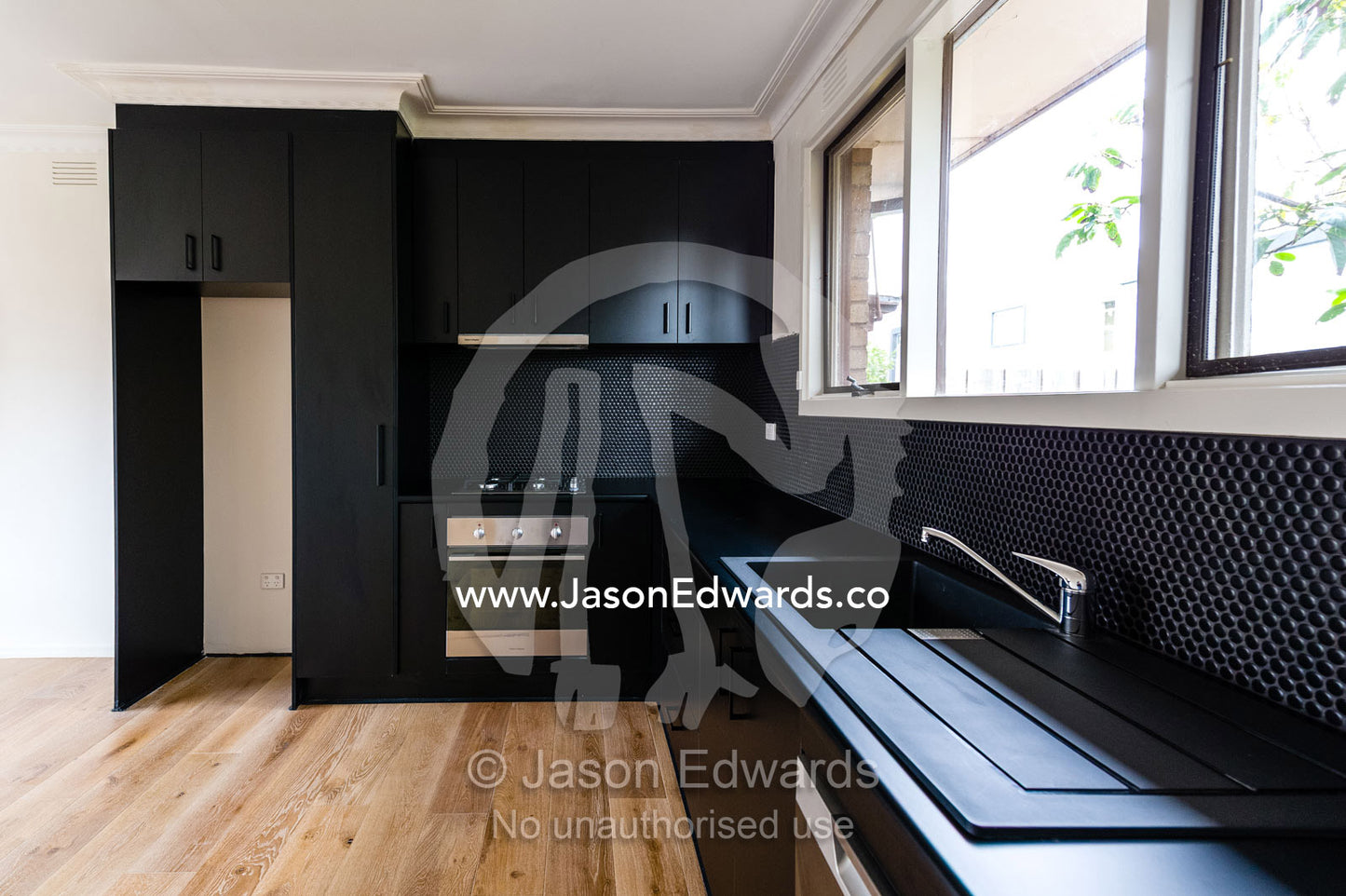 A black modern sink, oven and range cooker in a kitchen in an inner city apartment. Brunswick, Melbourne, Victoria, Australia.