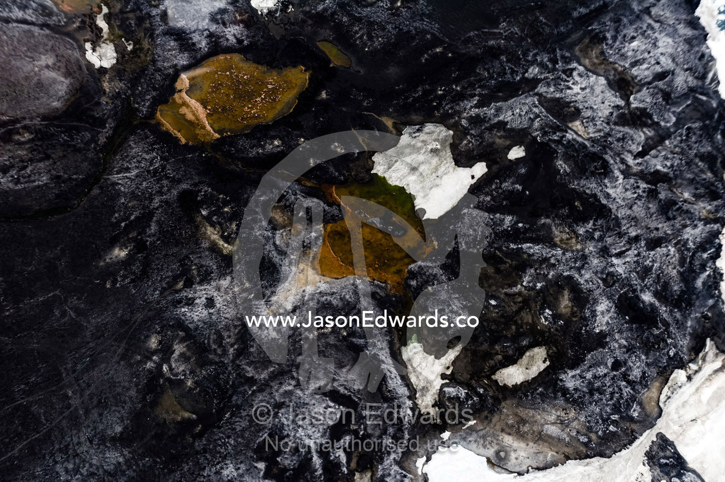 An aerial view of a barren lunar landscape surrounded by ice. Cape Evans, Ross Island, Antarctica