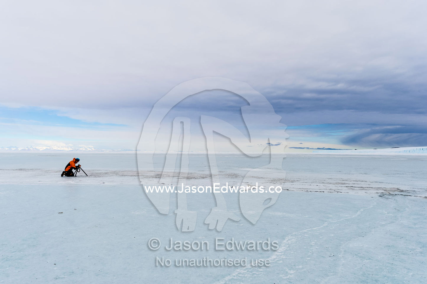A cameraman filming on the sea ice in Antarctica. Scott's Hut, Cape Evans, North Bay, Ross Island, Antarctica.