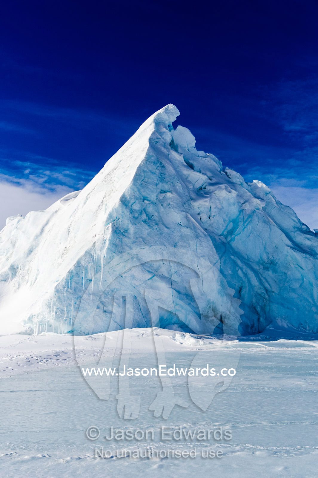 An enormous jagged iceberg trapped in frozen sea ice. Erebus Bay, McMurdo Sound, Cape Evans, Ross Island Antarctica.