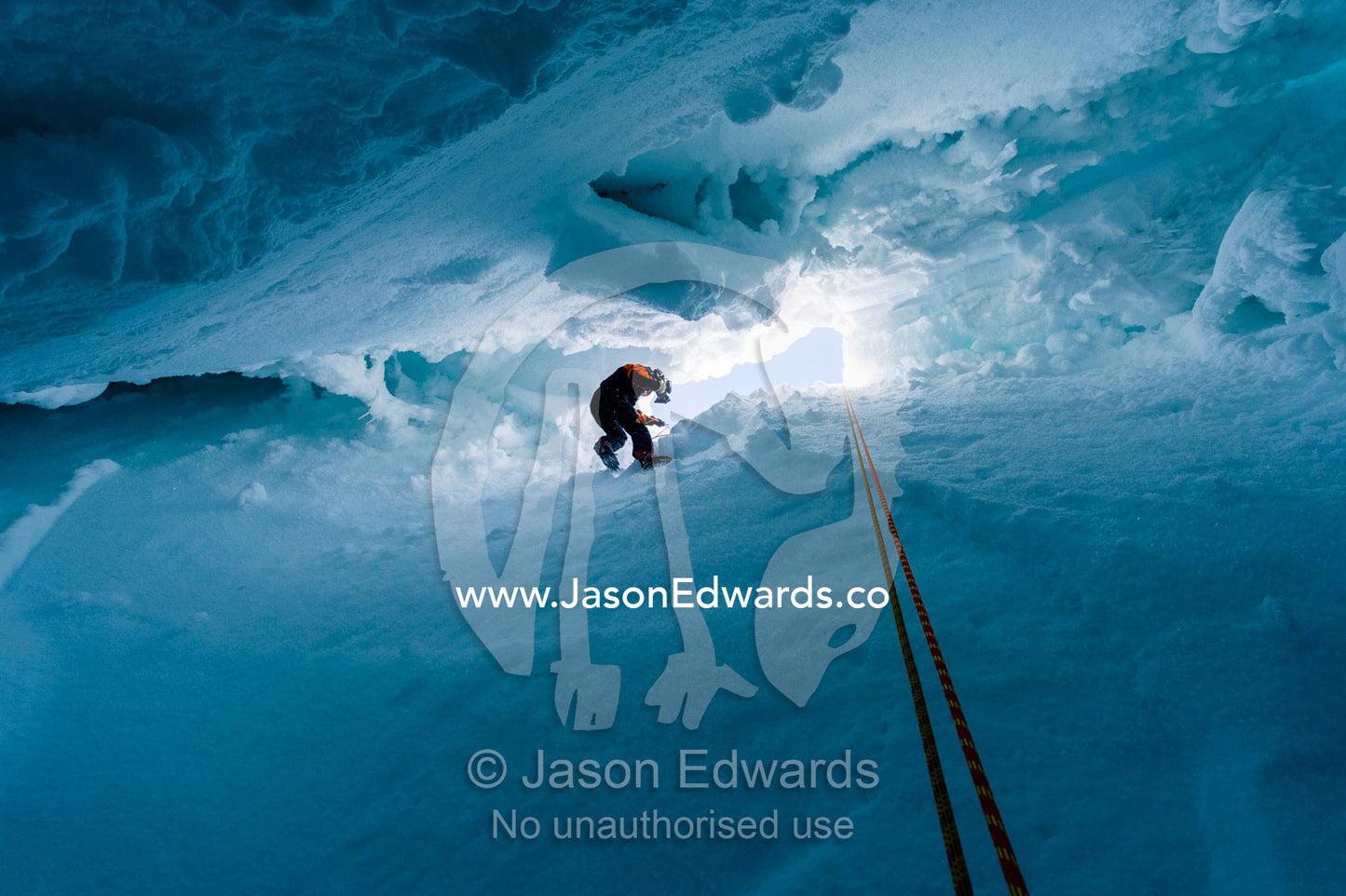 A cameraman descending the sheer icy walls of a crevasse on the slopes of Mount Erebus in Antarctica. Silver City Ice Fall, Hut Point Peninsula, Ross Island Antarctica.