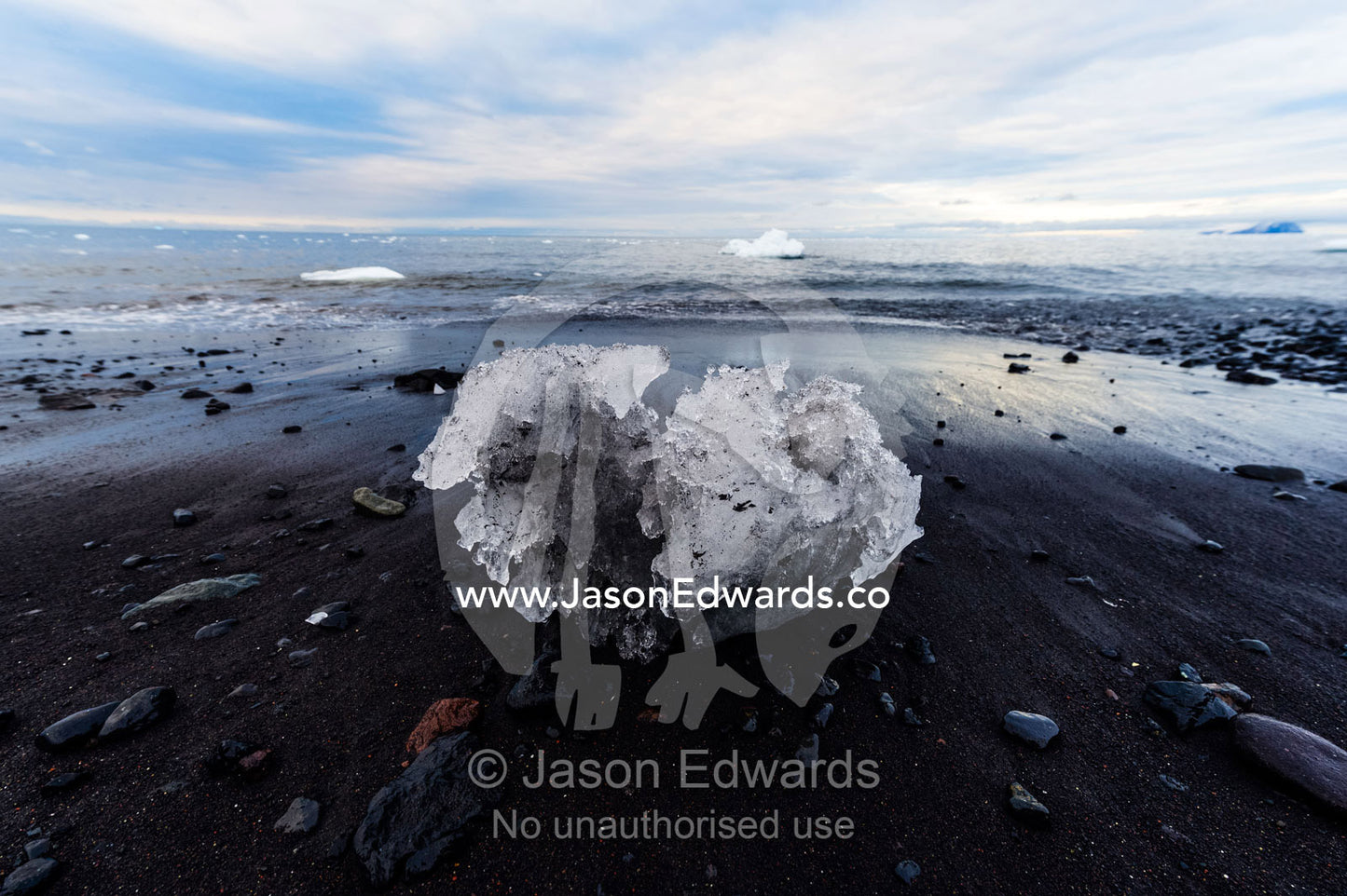 A boulder of glacier ice resting on a black volcanic beach in Antarctica. Caughley Beach, Cape Bird, Ross Island, Antarctica.