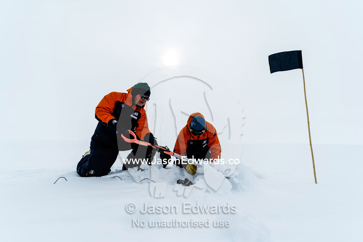Volcanologists on a frozen plain change batteries in a volcano research sensor. Windless Bight, Hut Point Peninsula, Ross Island, Antarctica.