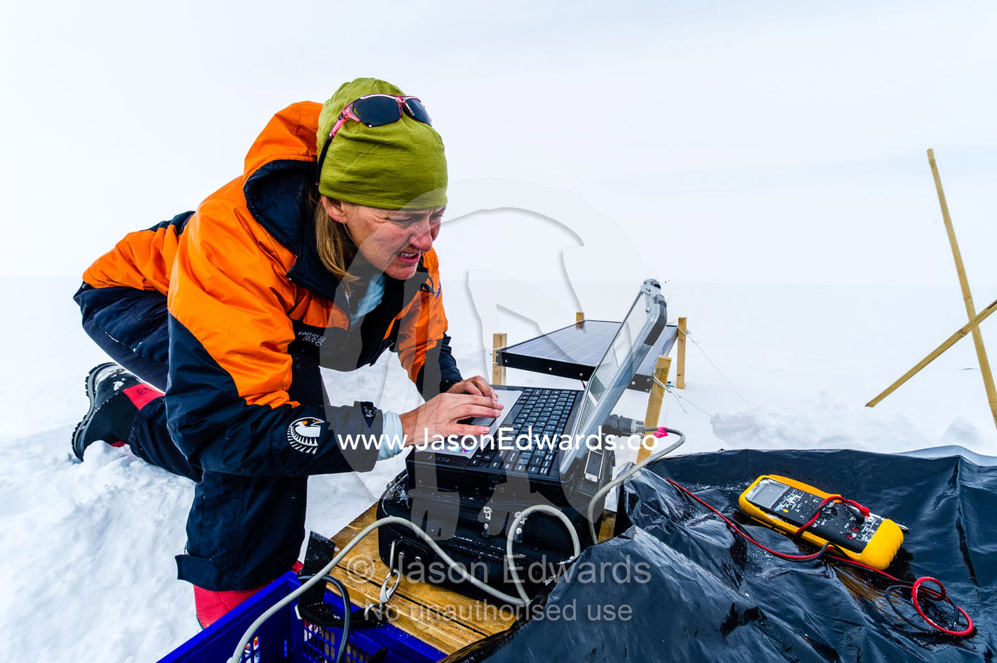 Volcanologists on a frozen plain monitor a volcano research sensor with a laptop computer. Windless Bight, Hut Point Peninsula, Ross Island, Antarctica.