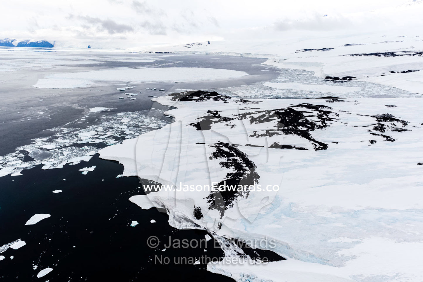 Melting sea ice, icebergs and ice cliffs along a rugged and inhospitable bay in Antarctica. Maumee Bight, Wohlschlag Bay, Ross Island, Antarctica.