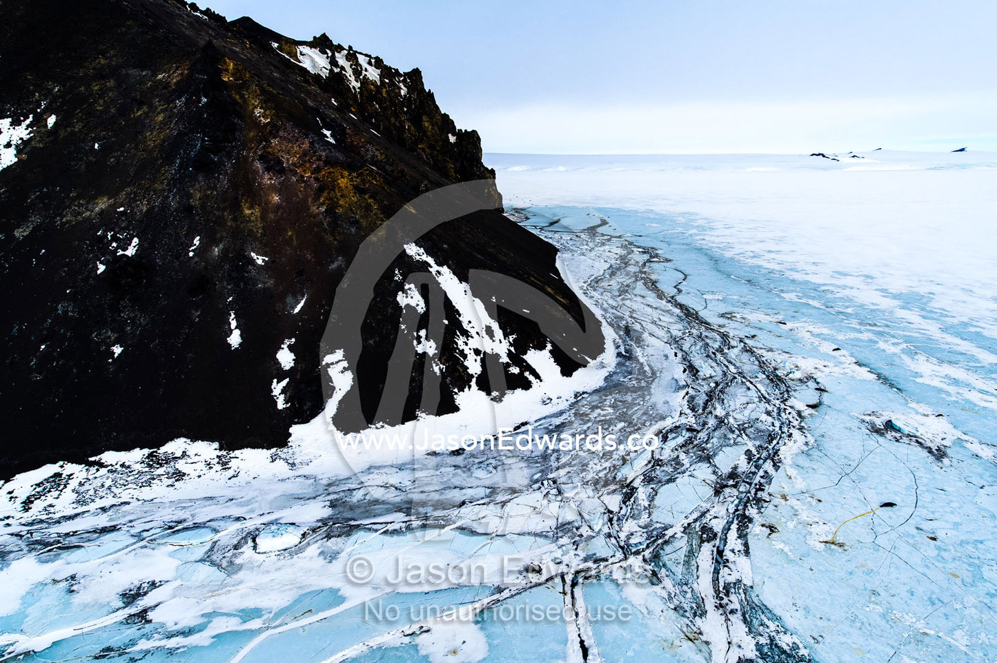 Pressure ridges in the sea ice crack against sheer rocky cliffs in Antarctica. Turks Head, Turks Head Bay, Ross Island, Antarctica.