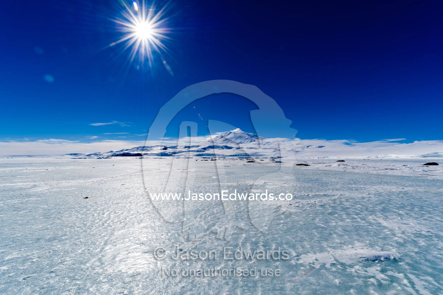 The polished surface of the sea ice blown clear of snow by strong winds. Hutton Cliffs, Erebus Bay, McMurdo Sound, Ross Island, Antarctica.