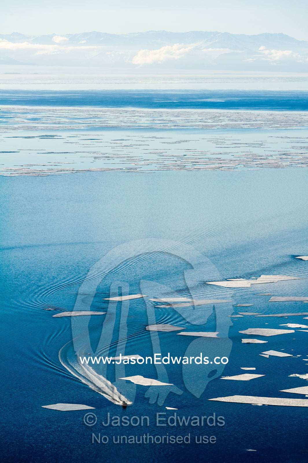 An inflatable zodiac transports sailors from a US naval vessel through sea ice that is breaking up. McMurdo Sound, McMurdo Station, Ross Island, Antarctica.