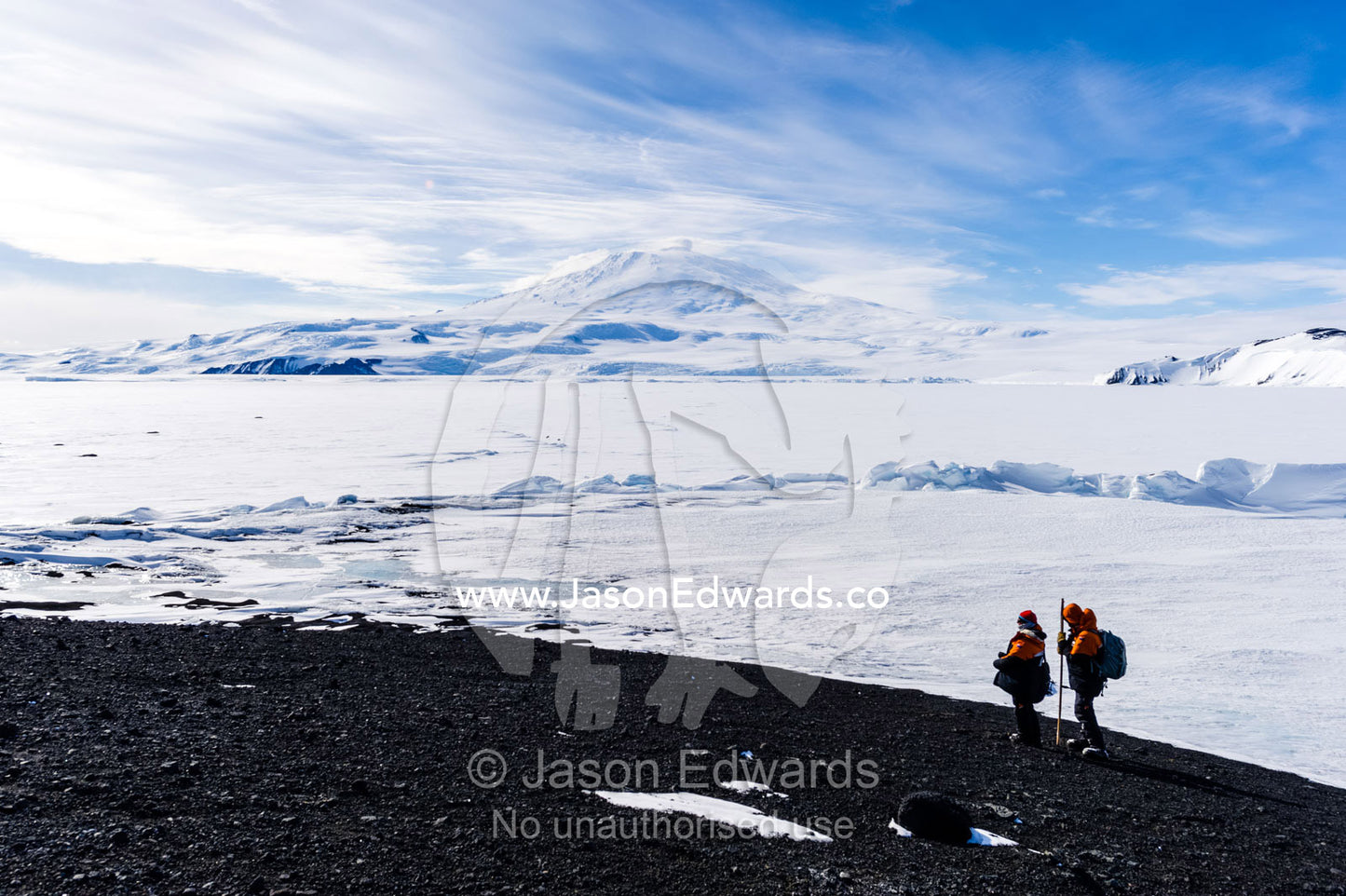 Researchers descend a mountain overlooking the frozen sea ice and Mount Erebus. Turtle Rock, Erebus Bay, McMurdo Sound, Ross Island, Antarctica.