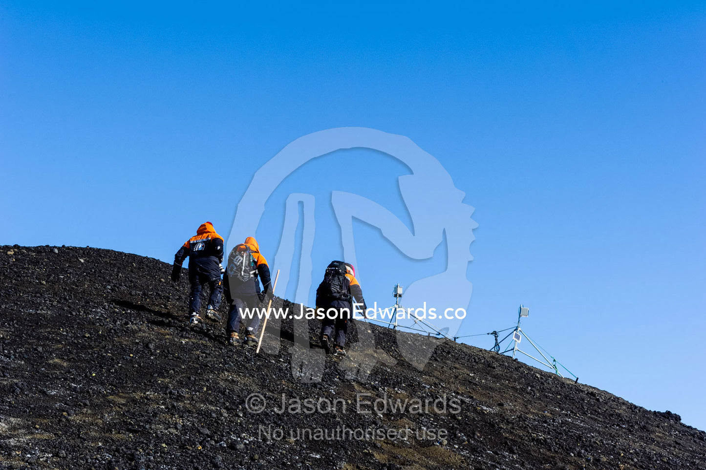 Scientists climb the slope of a volcanic island to check their camera equipment. Turtle Rock, Erebus Bay, McMurdo Sound, Ross Island, Antarctica.