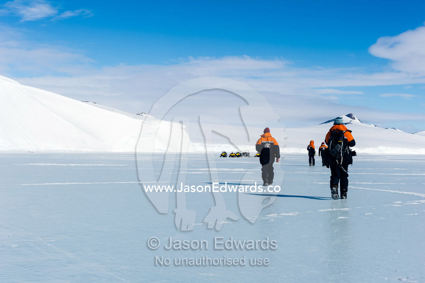 Marine mammal researchers walking across the polished surface of the sea ice. Hutton Cliffs, Erebus Bay, McMurdo Sound, Ross Island, Antarctica.