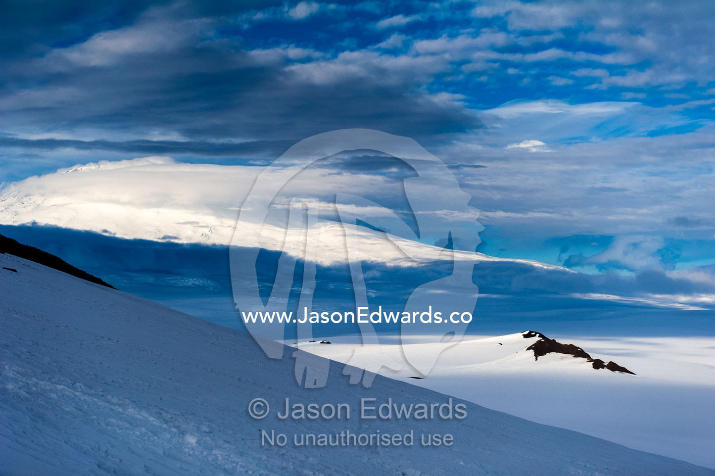 A snow-covered mountain slope looking towards Mount Erebus an active volcano. Breached Cone, Castle Rock, Hut Point Peninsula, Ross Island, Antarctica.
