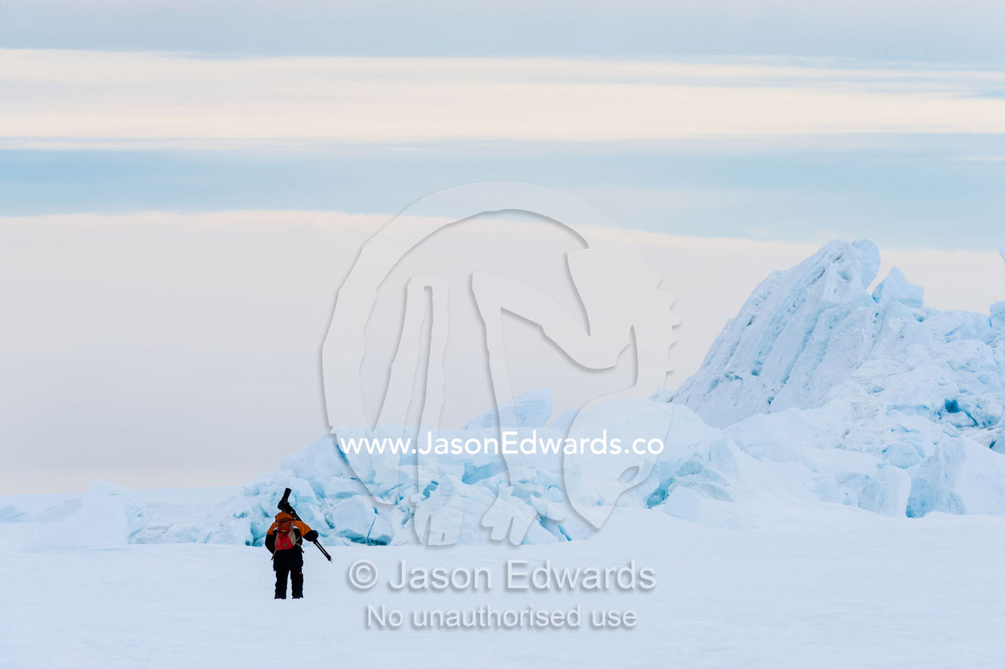 A photographer carries his tripod and camera across the sea ice to photograph pressure ridges. Turtle Rock, Erebus Bay, McMurdo Sound, Ross Island, Antarctica.