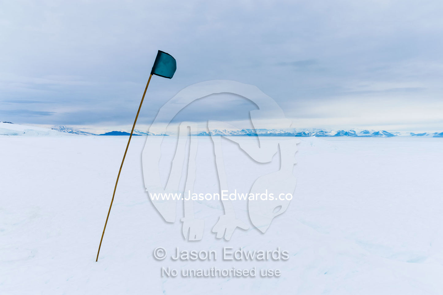 A green flag highlights a safe route across the sea ice. Turtle Rock, Erebus Bay, McMurdo Sound, Ross Island, Antarctica.
