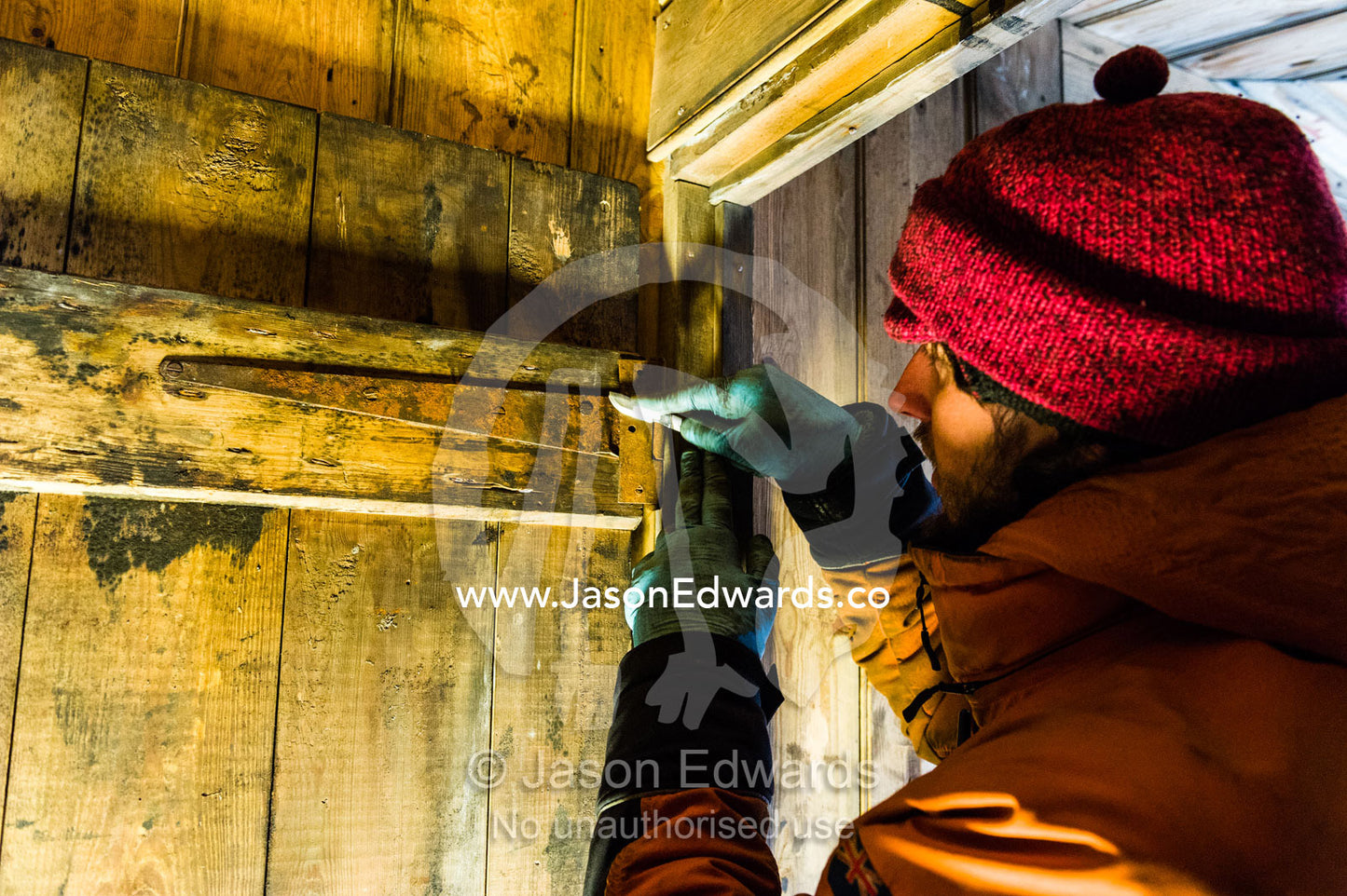 An expert from the Antarctic Heritage Trust working with a small blade to remove rust from a door in Discovery Hut. Discovery Hut, Hut Point, Ross Island, Antarctica.