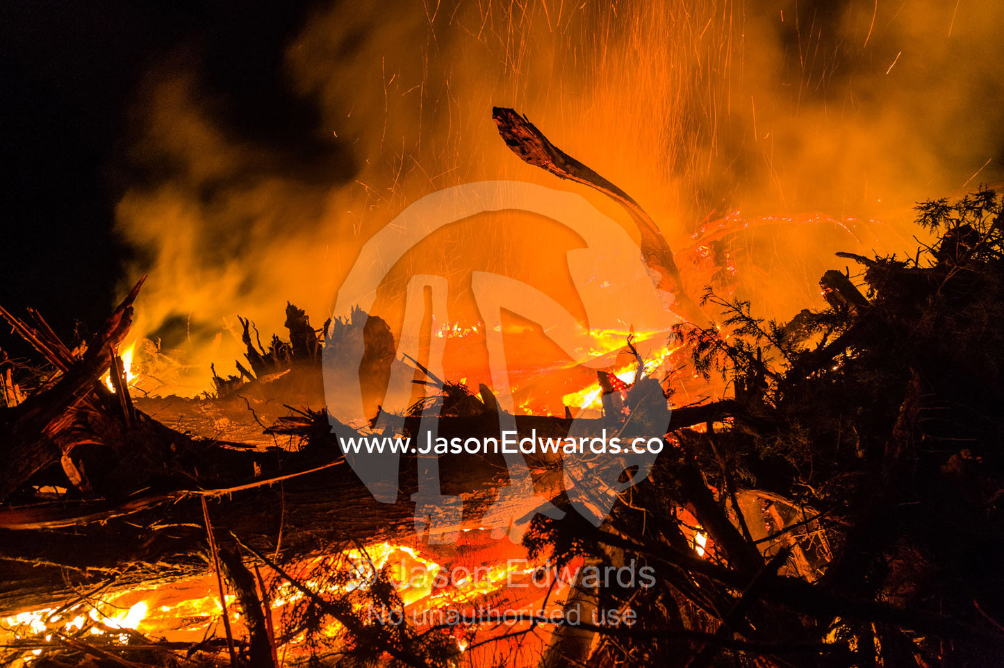 Flames and sparks fly into the air as a farmer burns surplus timber in a bonfire on his farm during winter. Bambra, Victoria, Australia.
