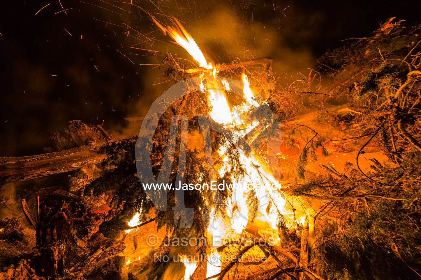 Flames and sparks fly into the air as a farmer burns surplus timber in a bonfire on his farm during winter. Bambra, Victoria, Australia.