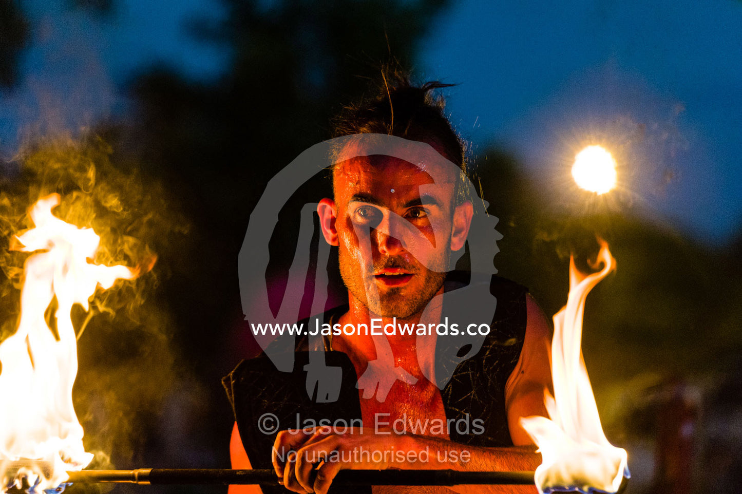 A fire performer dazzles the crowd at an open-air market by throwing a flaming baton. Mindil Beach Sunset Markets, Darwin, Northern Territory, Australia.