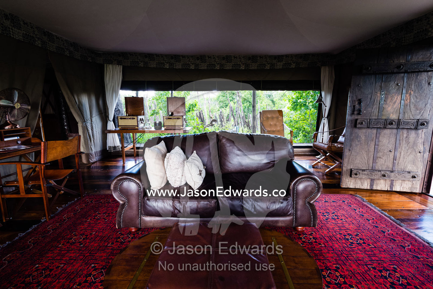 A leather sofa and antique furniture in the sitting room of a luxurious tented safari camp. Zarafa Camp, Zibadianja Lagoon, Savute Channel, Linyanti, Botswana.