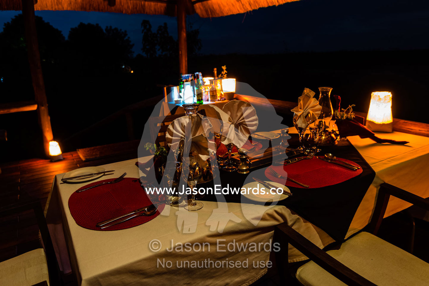 A dining table set for dinner on the verandah of a luxury safari camp tent. Selinda Camp, Selinda Reserve, Linyanti Region, Northern Botswana.