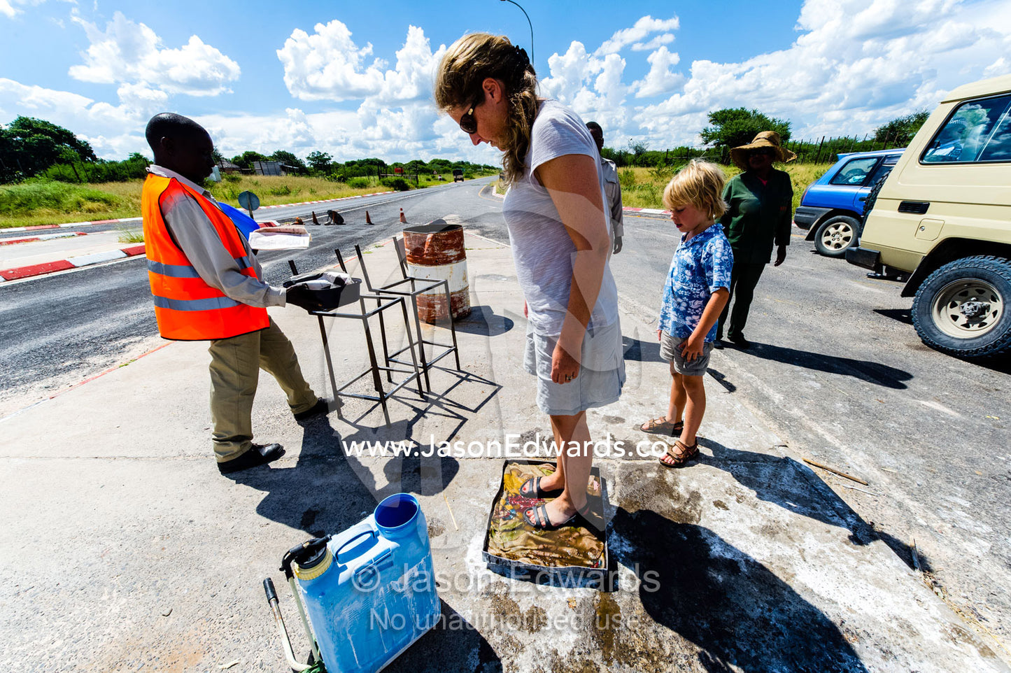 Tourists washing their shoes in antiseptic foot baths to prevent the spread of agricultural diseases. Kalahari Desert, Botswana.