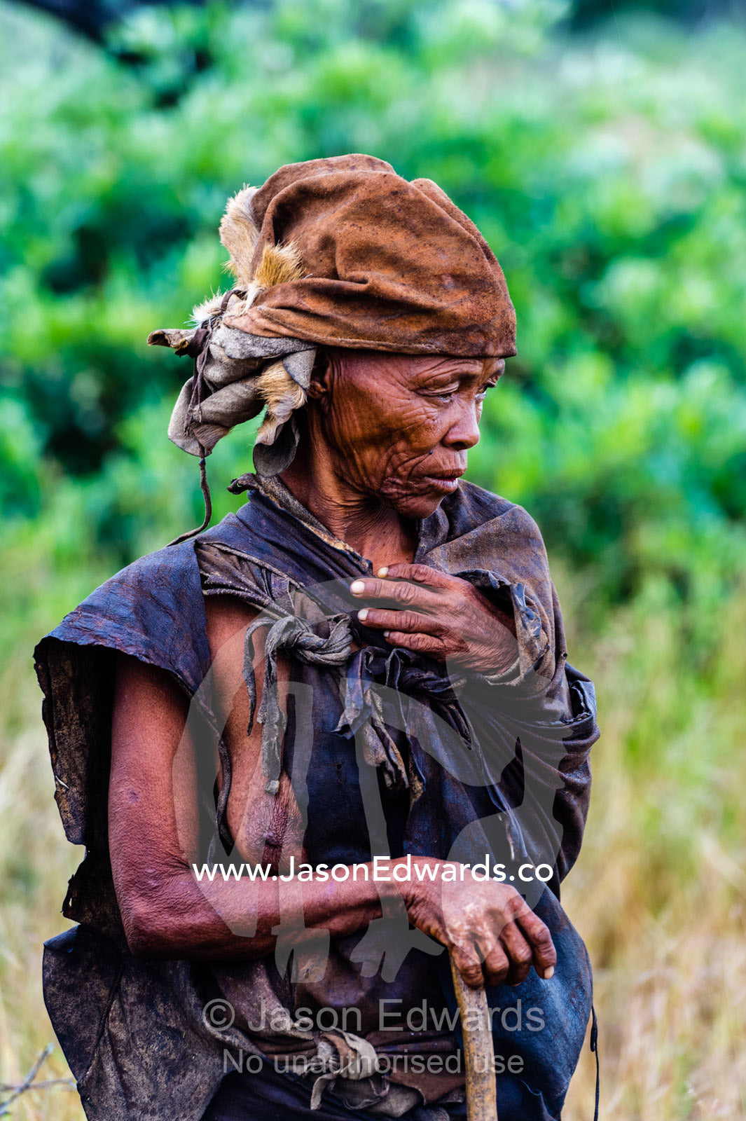 A San Bushmen woman wearing leather animal skins and hat. Kalahari Desert, Botswana.
