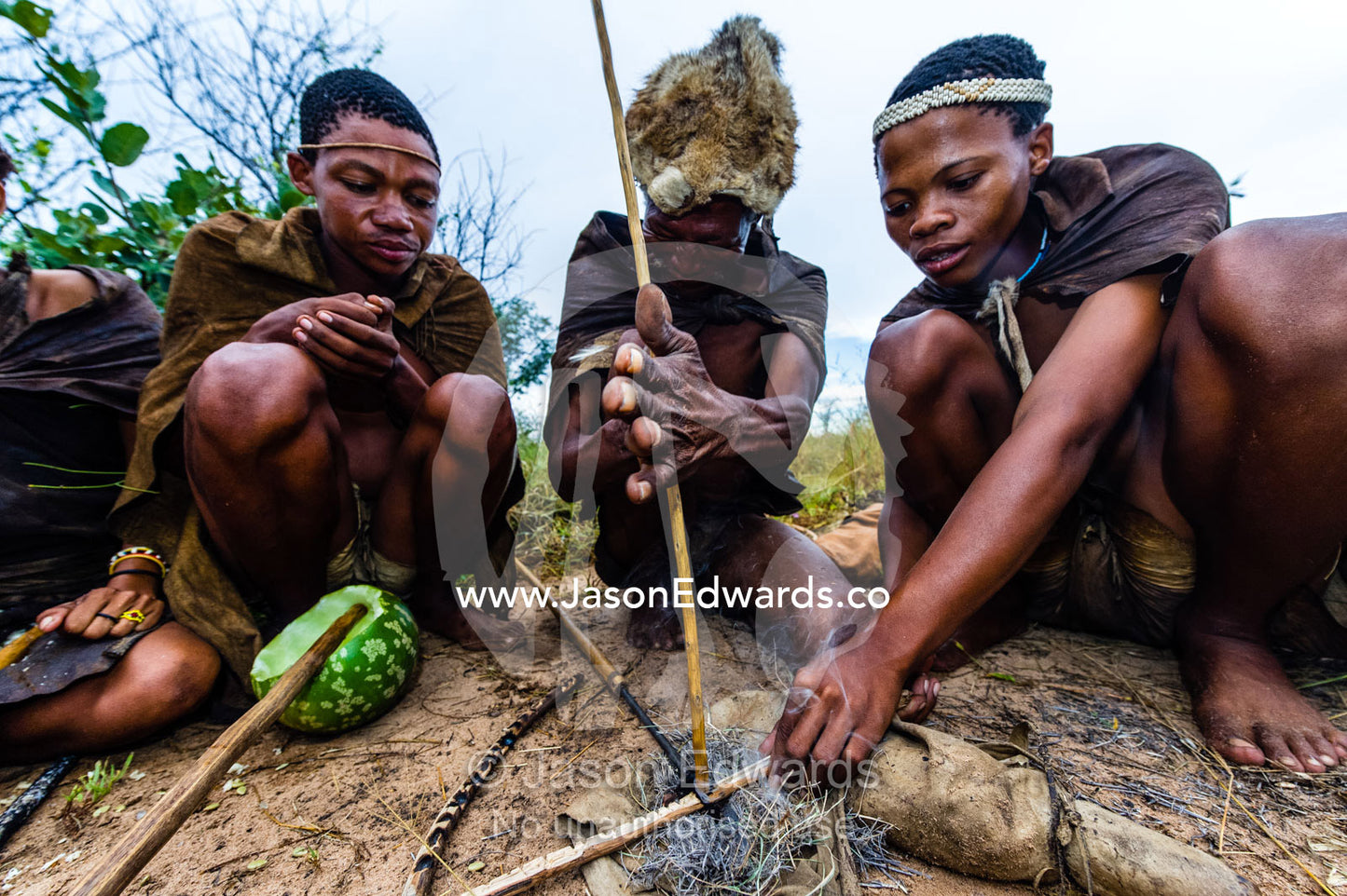 San Bushmen starting a fire using dry grass kindling, a wooden drill of hard wood and a soft wood fire board. Kalahari Desert, Botswana.