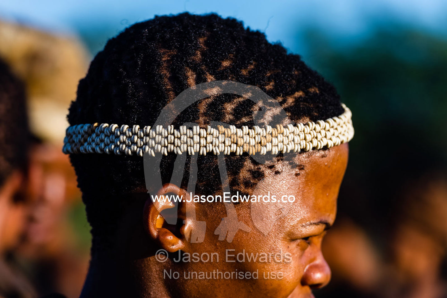 A young San Bushmen wearing an Ostrich egg shell head band. Kalahari Desert, Botswana.