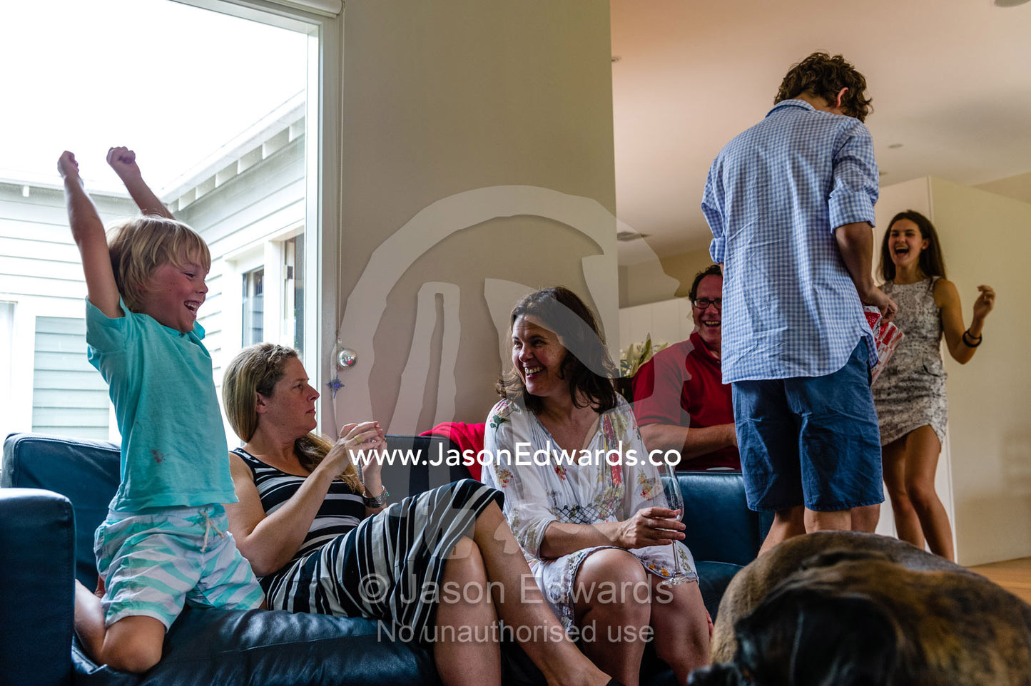 A boy celebrates as his family plays Kris Kringle on Christmas day where gifts are competitively exchanged for fun. Malvern East, Melbourne, Victoria, Australia.