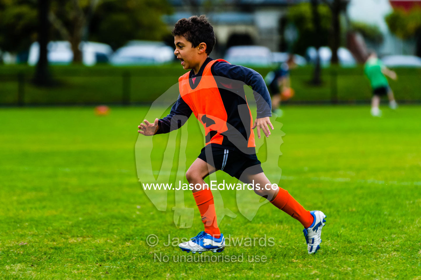 A boy learning to play Australian rules football on a sports field. Edinburgh Gardens, North Fitzroy, Melbourne, Victoria, Australia.