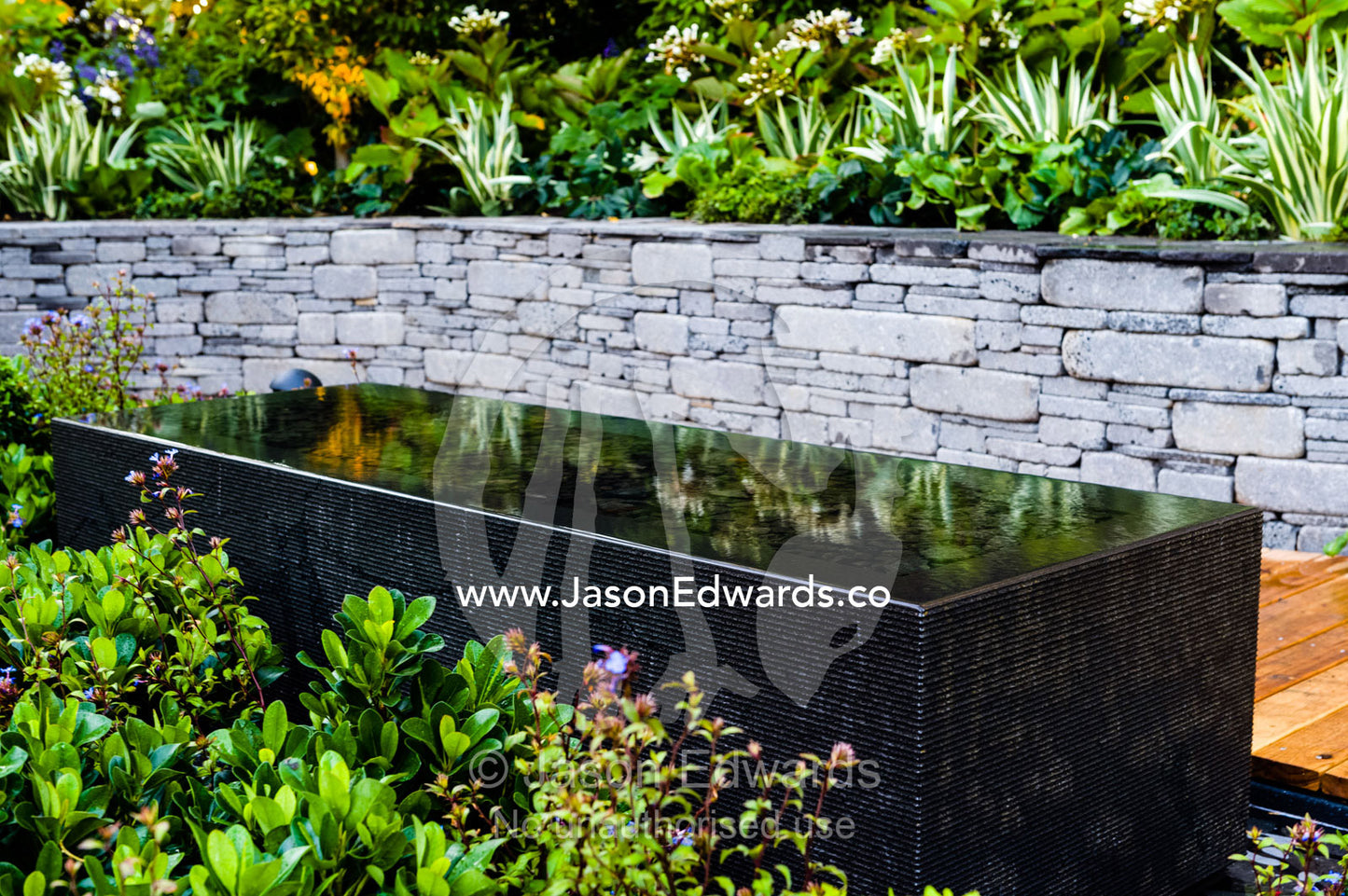 An architecturally designed outdoor patio and garden setting with a blue stone pond at a garden show. Melbourne International Flower and Garden Show, Carlton Gardens, Carlton, Melbourne, Victoria, Australia.