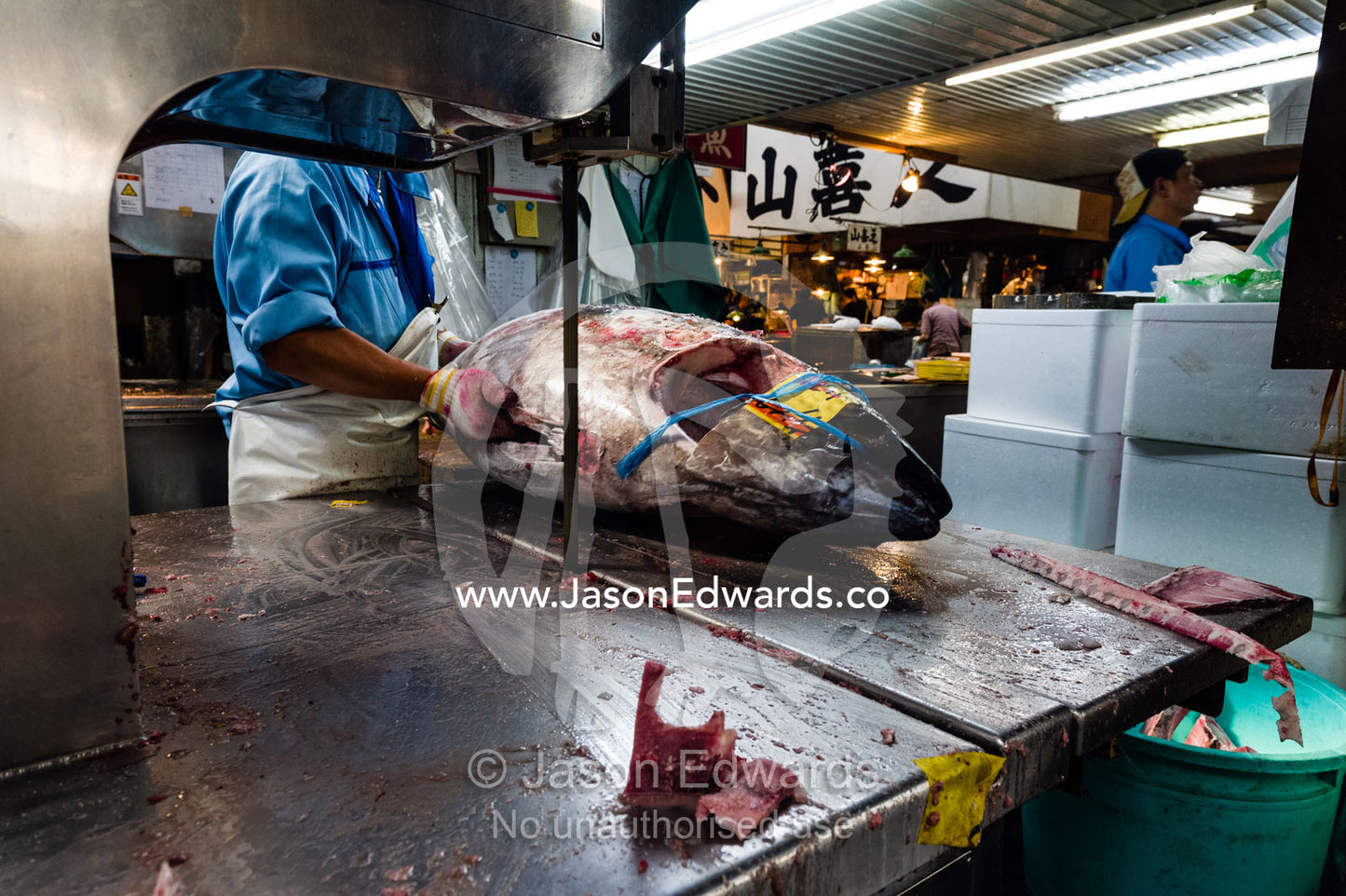 A band saw cutting the head off a frozen tuna in a fish market. Tsukiji Market, Tsukiji, Chuo, Tokyo.