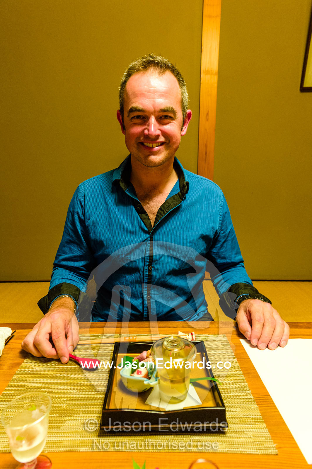 A man sitting at a Japanese table called a Zataku to eat Kaiseki a traditional multi-course Japanese dinner. Unryu Onsen, Izu Peninsula, Shizuoka Prefecture, Japan.