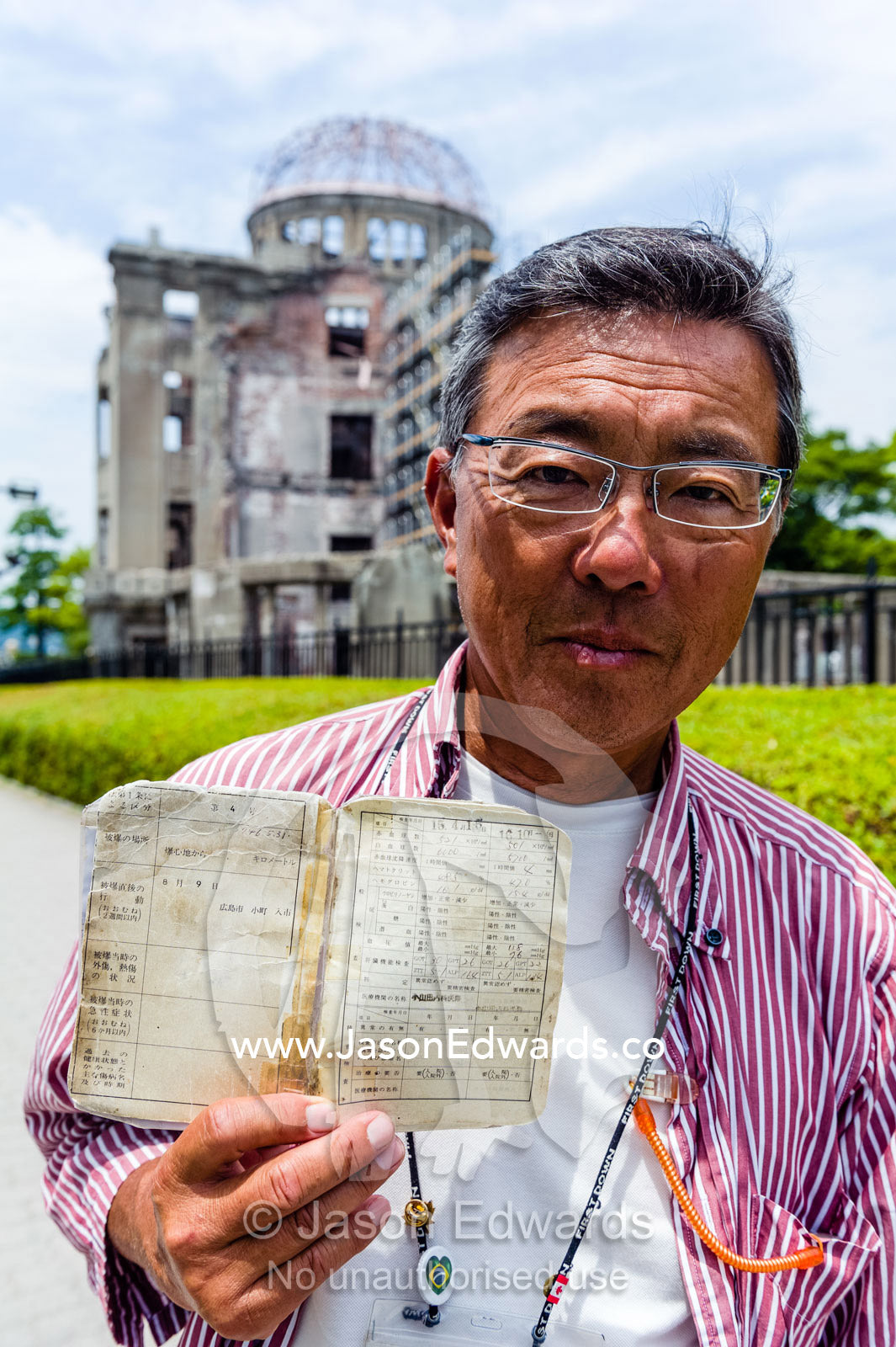 An in-utero survivor of the Hiroshima Atomic Bomb attack displays his official Japanese survivor documents. Hiroshima Peace Memorial Park, Hiroshima, Honshu Island, Japan.