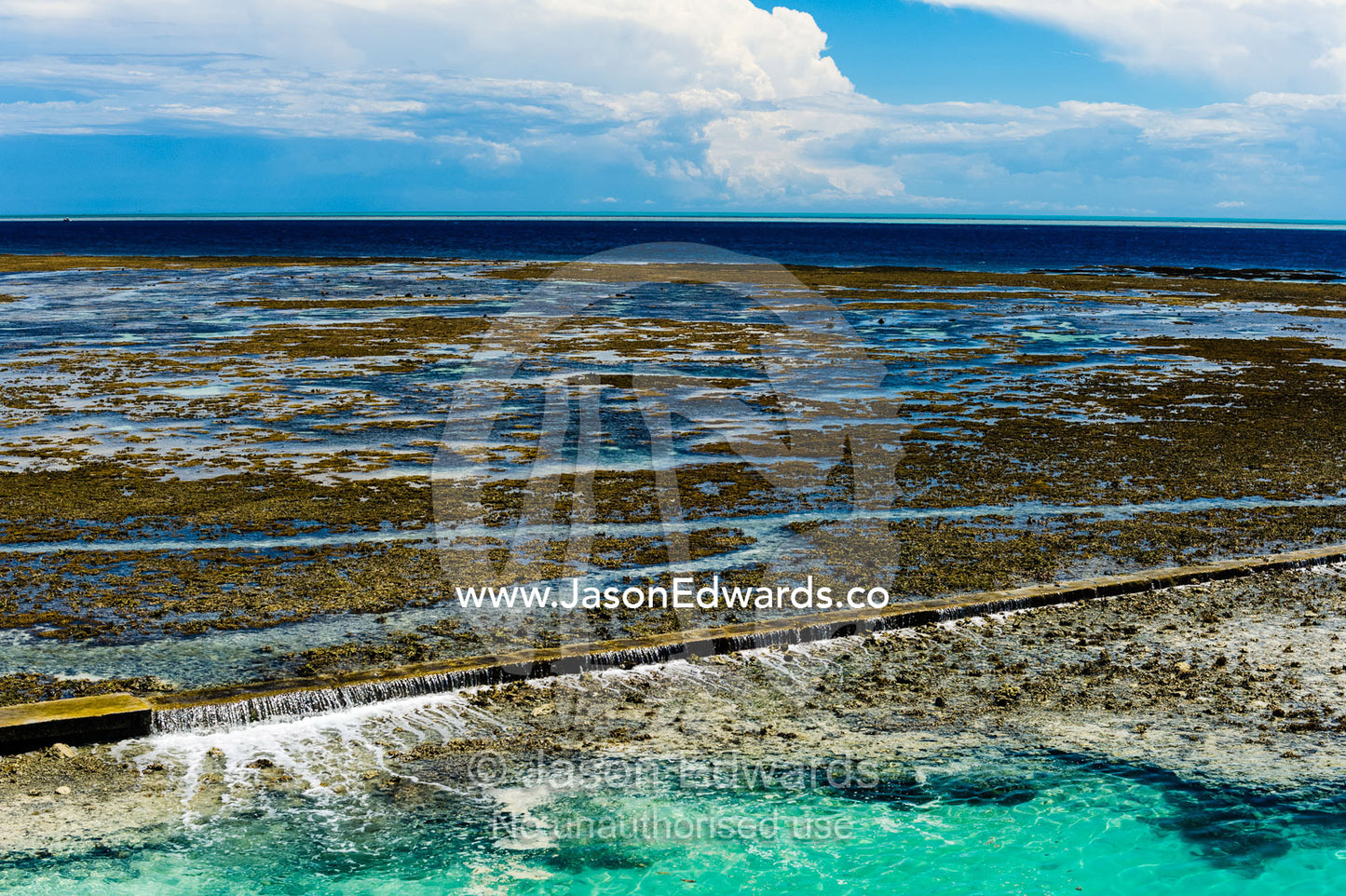 Water from the rising tide spills over a coral reef and harbour retaining wall. Heron Island Harbour, Heron Island, Great Barrier Reef, Queensland, Australia.