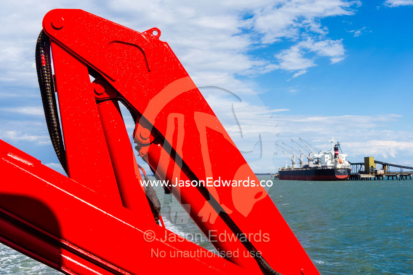 A bright red crane on a passenger ferry used for lifting cargo. Gladstone, Queensland, Australia.