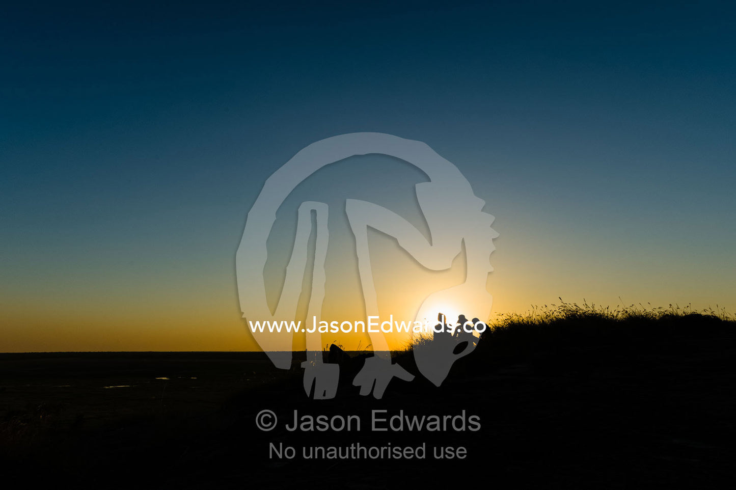 The silhouette of friends watching a famous Top End, sunset from an escarpment over a floodplain. Ubirr, Nadab floodplain, Kakadu National Park, Northern Territory, Australia.