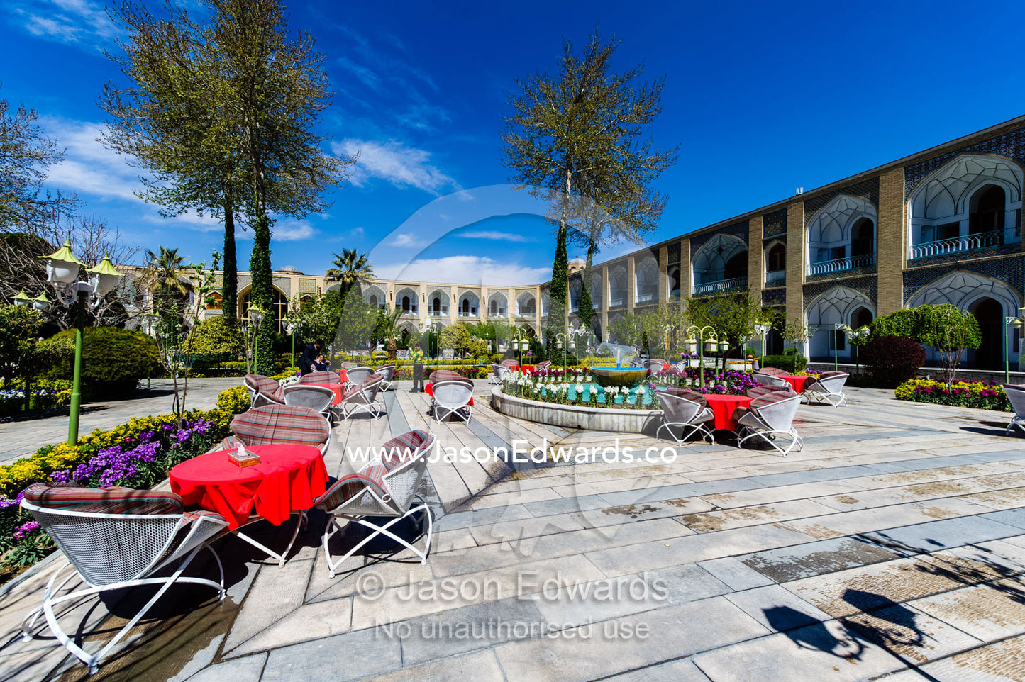 A patio dining area with tables and chairs in a caravanserai converted into a boutique hotel. The Abbasi Hotel, Isfahan, Isfahan Province, Islamic Republic of Iran.