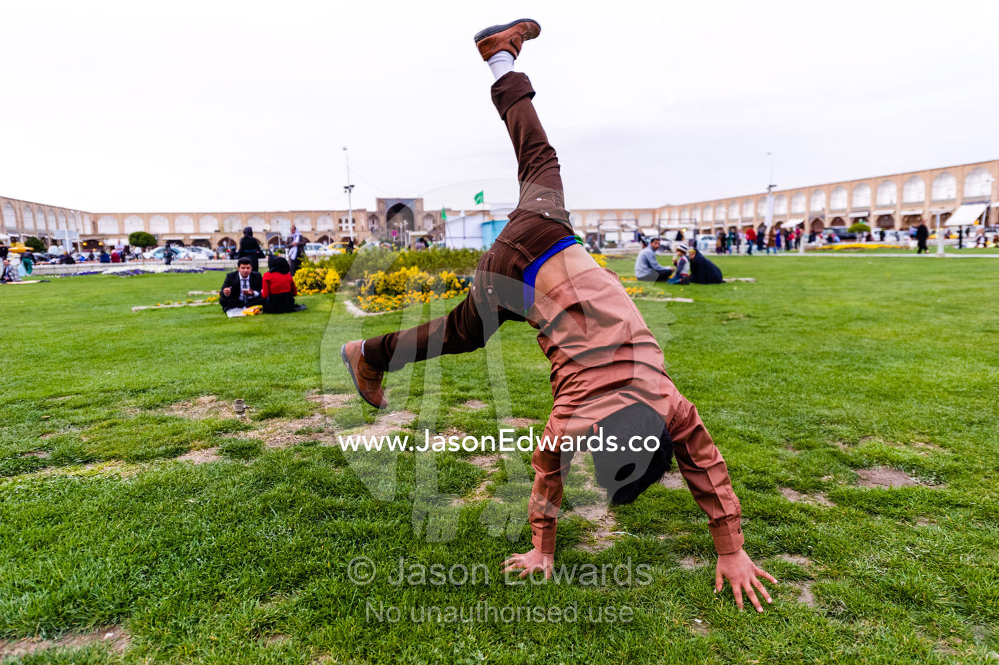 A boy doing cartwheels on the grass whilst on the New Year holiday. Naqsh-e Jahan Square, Isfahan, Isfahan Province, Islamic Republic of Iran.