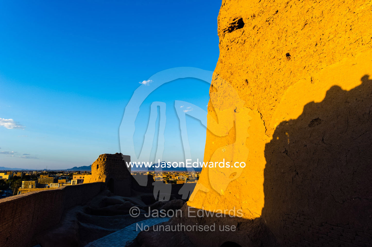 Sunset warms the walls of an ancient mud brick fortress overlooking the desert plain. Narin Castle, Meybod, Meybod County, Yazd Province, Islamic Republic of Iran.
