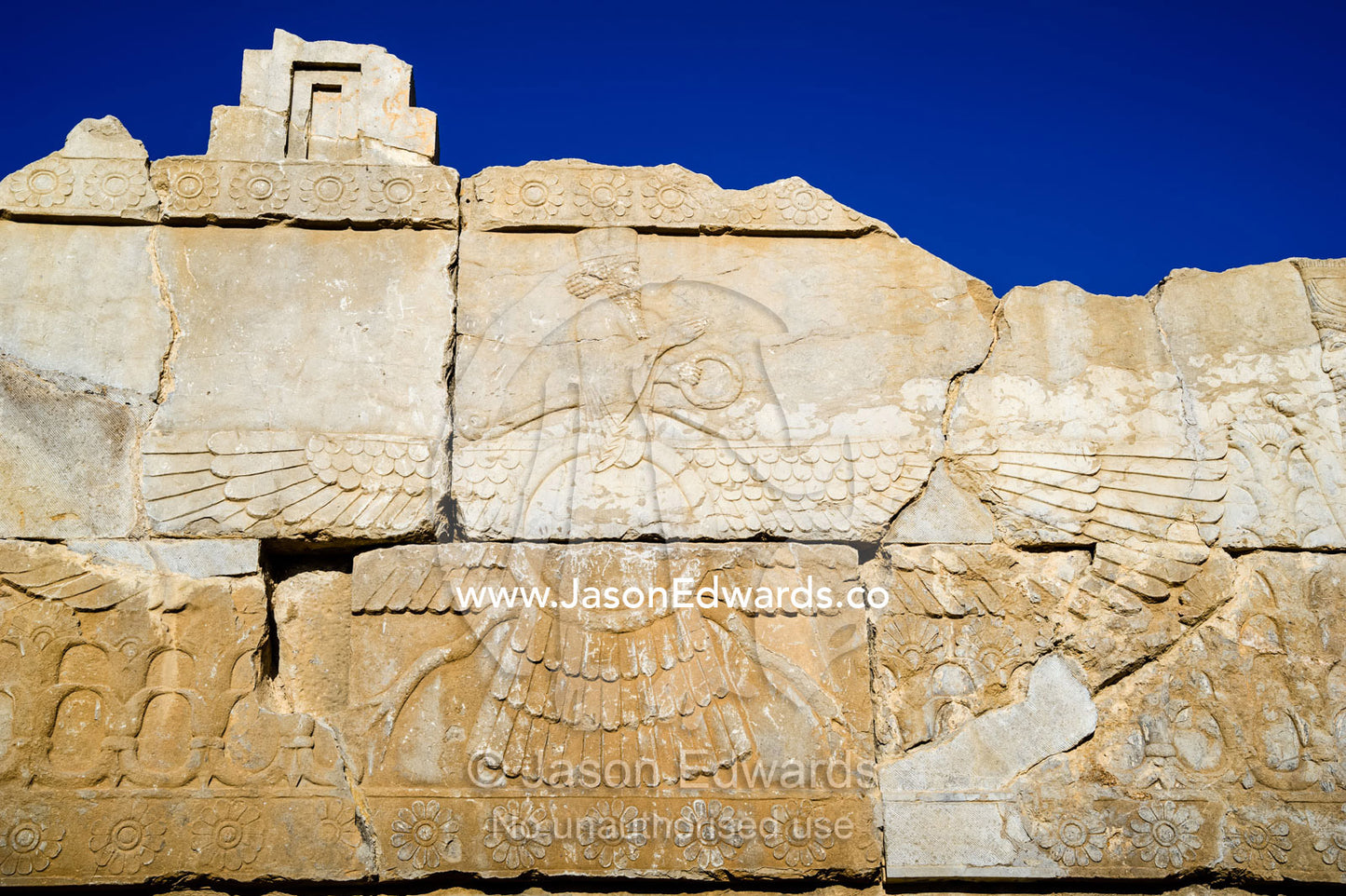 A symbol of the winged discs of Fravahr carved into a stone wall. Persepolis, Shiraz, Fars Province, Islamic Republic of Iran.