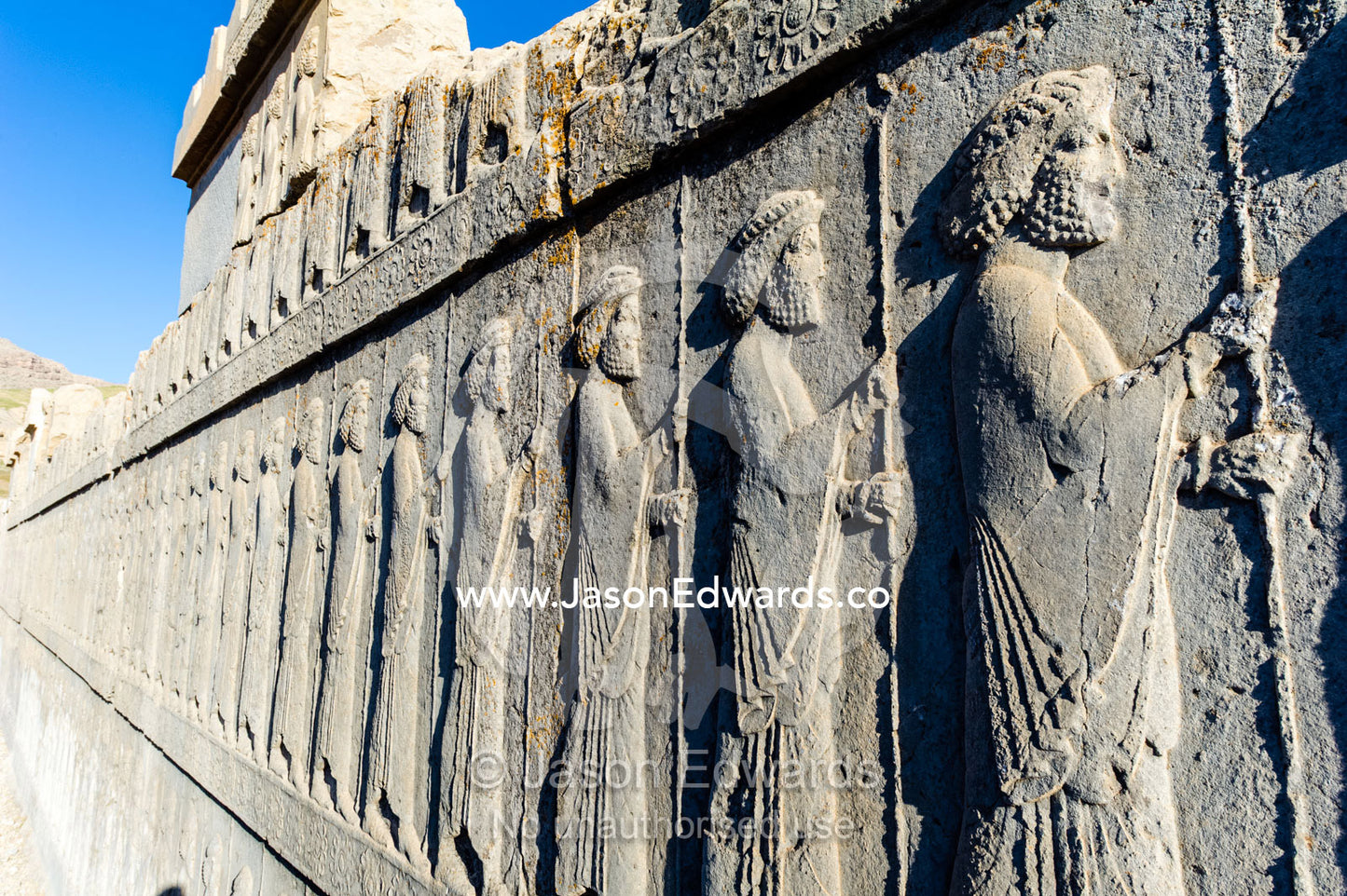 A limestone frieze of immortal guards carrying spears carved into a stone wall at Persepolis. Persepolis, Shiraz, Fars Province, Islamic Republic of Iran.
