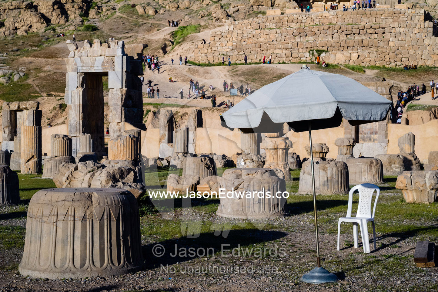 A security guard's plastic chair and umbrella among the ancient ruins of Persepolis. Persepolis, Shiraz, Fars Province, Islamic Republic of Iran.