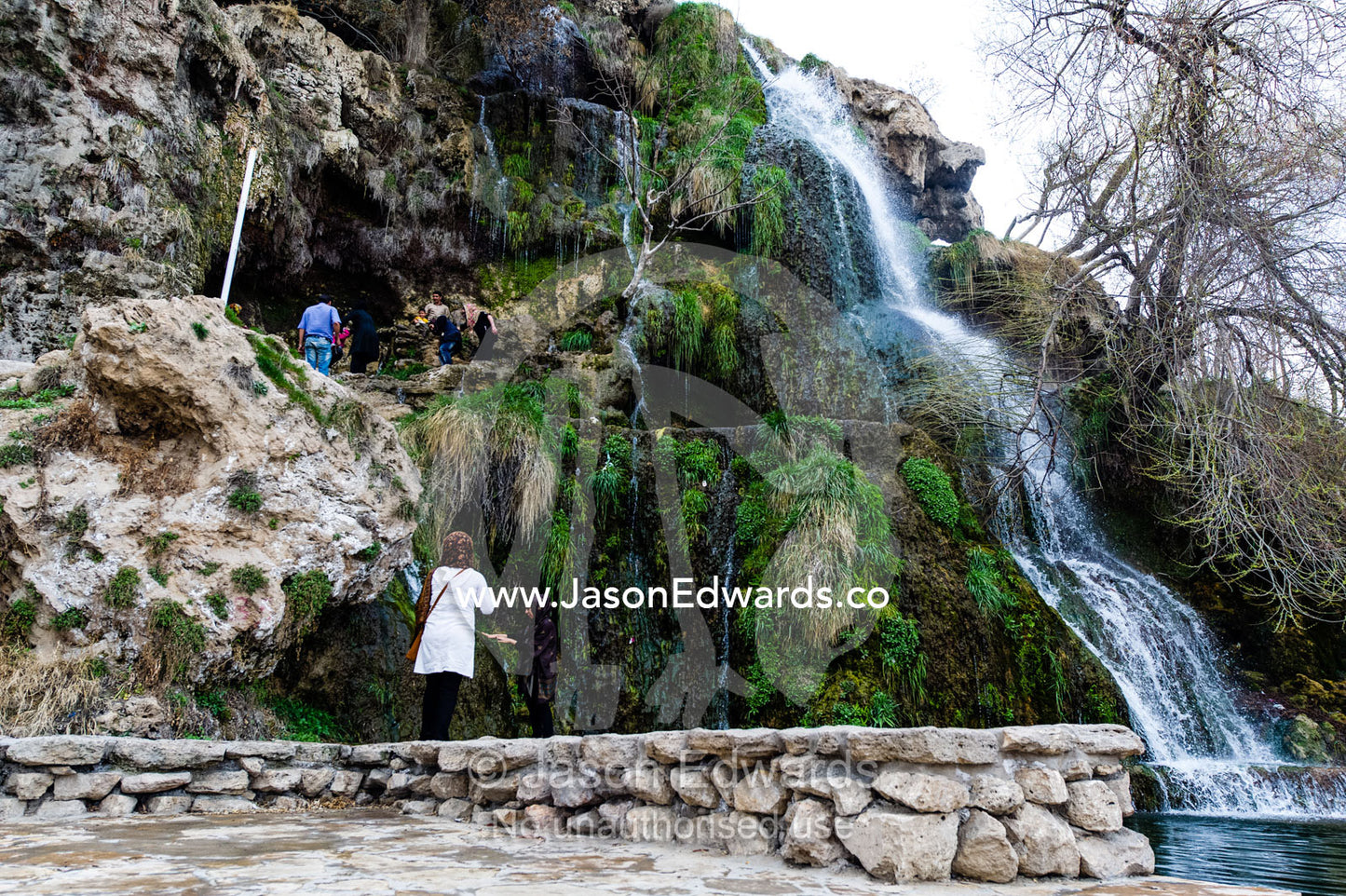 Tourists climb the cliff beside a small waterfall. Niasar, Neyasar District, Kashan County, Isfahan Province, Islamic Republic of Iran.