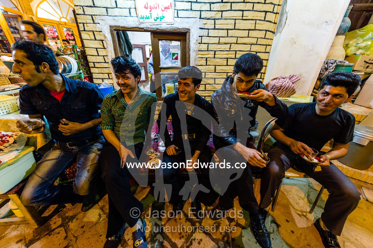 A group of friends taking a tea break from selling goods in an ancient bazaar. The Bazaar of Kashan, Kashan, Isfahan, Islamic Republic of Iran.