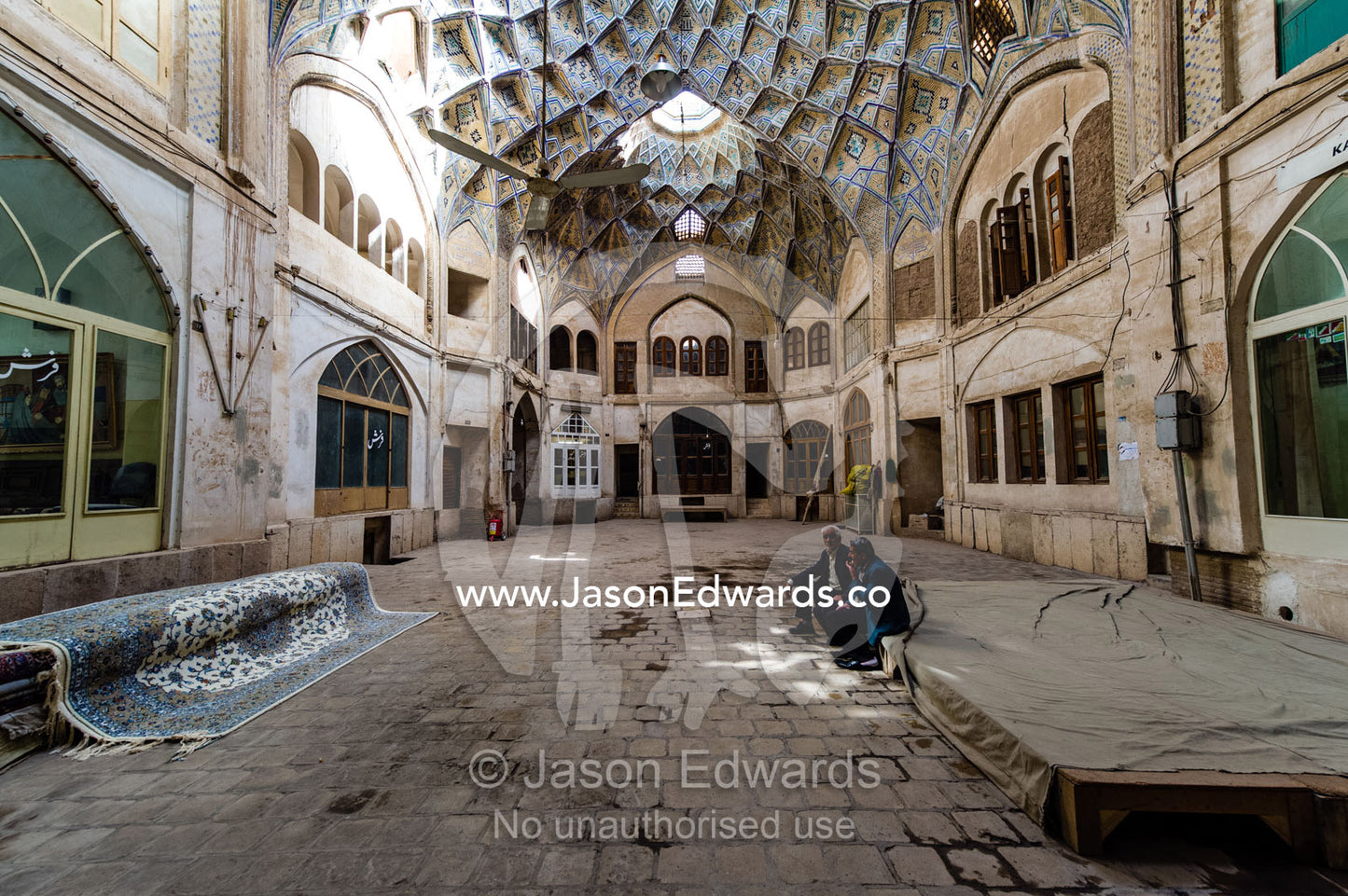 Persian carpet merchants display their goods in an ancient Bazaar. The Bazaar of Kashan, Kashan, Isfahan, Islamic Republic of Iran.