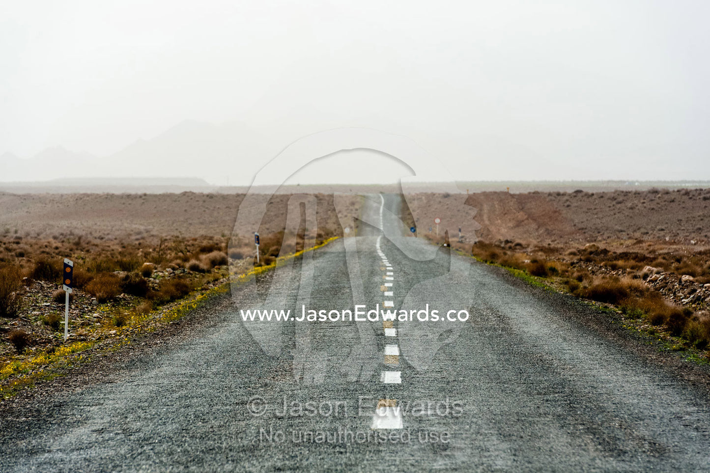 A bitumen road crosses a barren desert plain. Barzrud Rural District, Natanz County, Isfahan Province, Islamic Republic of Iran.