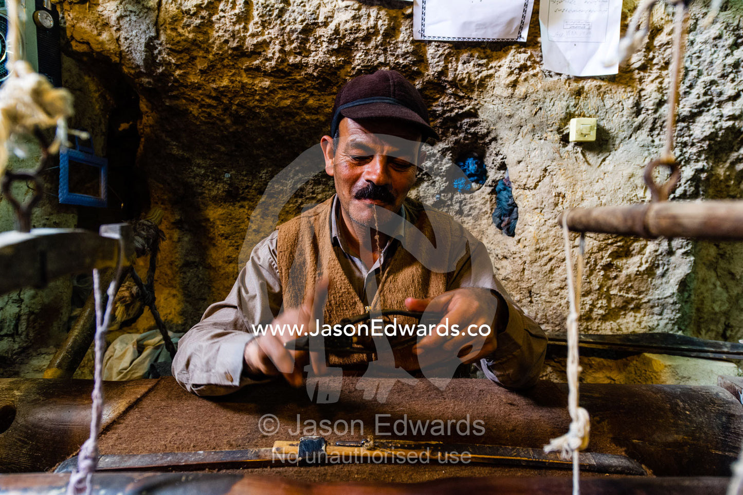 A man practicing traditional cloak weaving on an antique loom in a cave in the desert. Nain, Nain County, Isfahan Province, Iran.