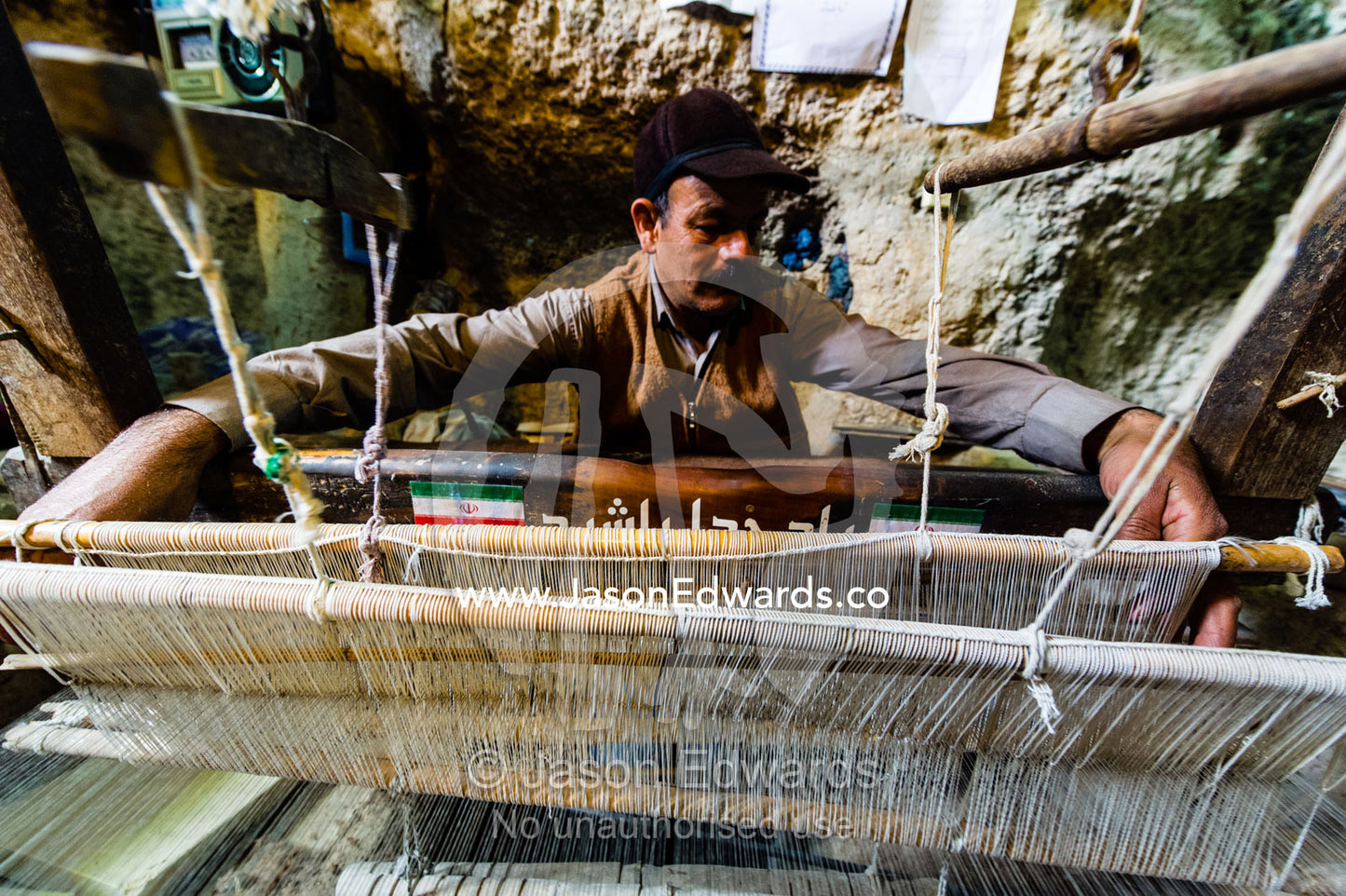 A man practicing traditional cloak weaving on an antique loom in a cave in the desert. Nain, Nain County, Isfahan Province, Iran.