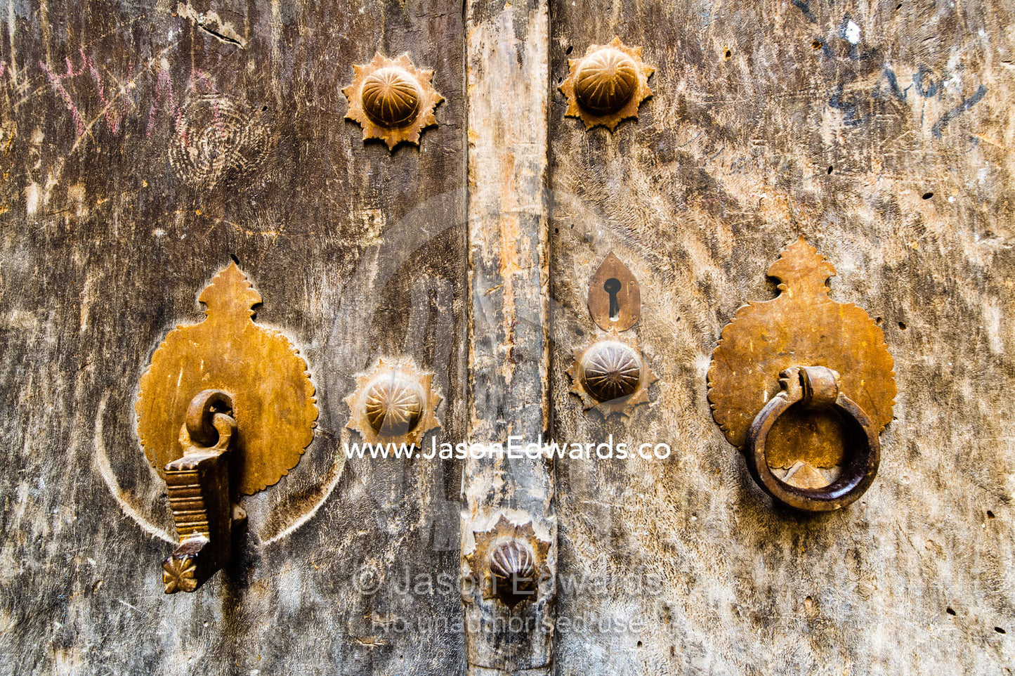 An old timber door with rusting antique tappers, one for the man and one for the woman. Yazd, Yazd Province, Islamic Republic of Iran.